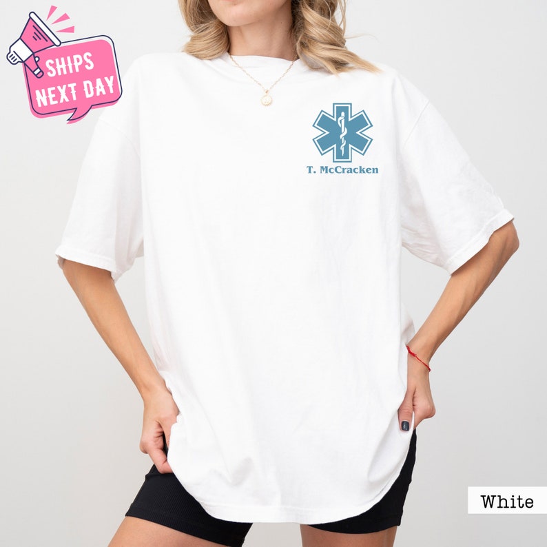 a woman wearing a white t - shirt with a blue cross on it