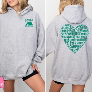 a woman wearing a grey hoodie with green writing on it