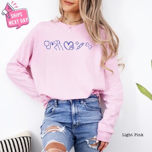 a woman wearing a pink sweatshirt and ripped jeans