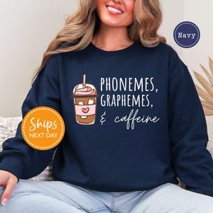 A woman wearing a navy blue sweatshirt with text and an illustration of a coffee drink.