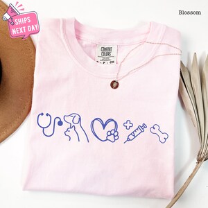 a pink t - shirt with blue writing on it next to a hat
