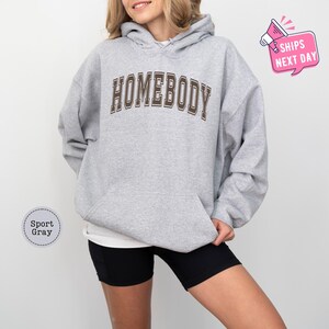 a woman wearing a grey hoodie with the word homeboy on it