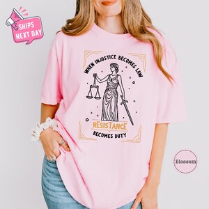 a woman wearing a pink t - shirt with a lady justice t - shirt on