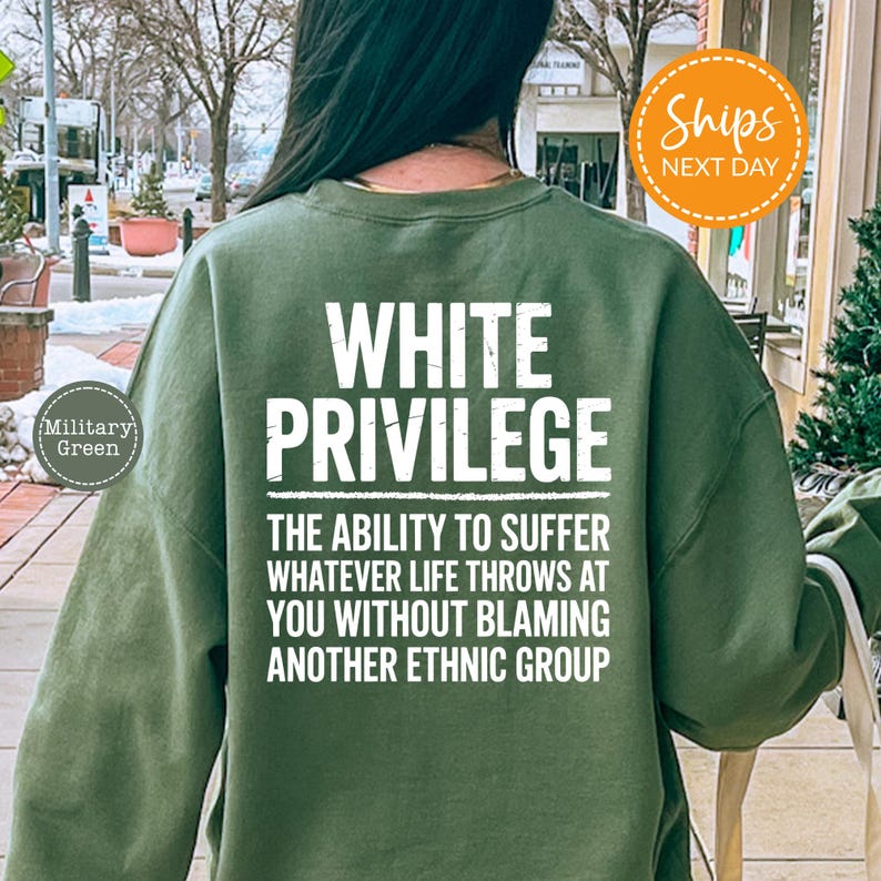 a person wearing a green sweatshirt with white text on the back. The text reads "WHITE PRIVILEGE" and "THE ability to suffer whatever life throws at you without Blaming another Ethnic group".