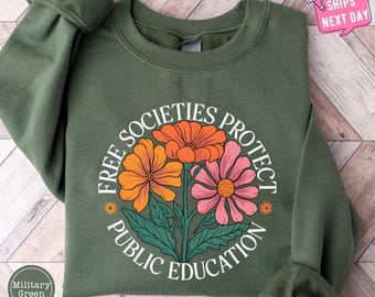 Puede incluir: Una sudadera verde con un gráfico circular blanco con el texto "Free Societies Protect Public Education" y tres flores estilizadas en naranja, rosa y amarillo.