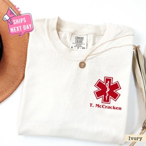 a white t - shirt with a red cross on it