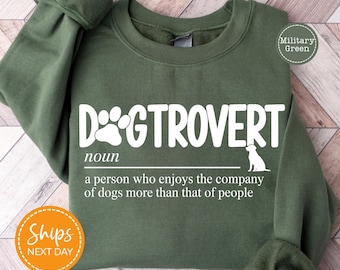 May include: Military green sweatshirt with the word "DOGTROVERT" in white, featuring a paw print and dog silhouette. The text defines "DOGTROVERT" as a person who enjoys the company of dogs more than people.