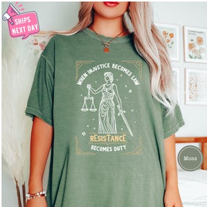 a woman wearing a green t - shirt with a picture of a lady holding a