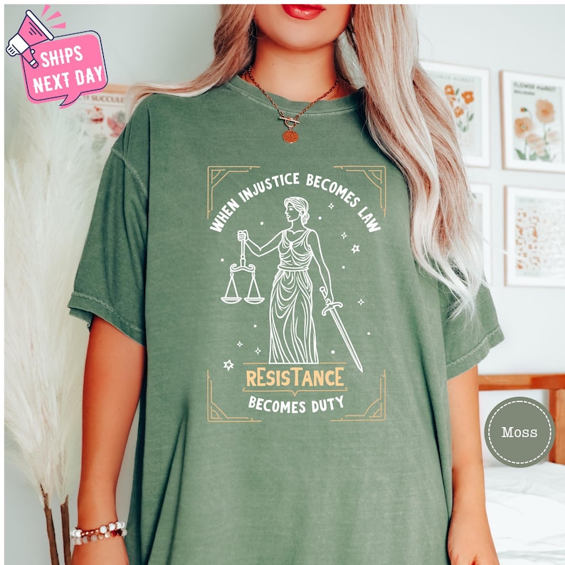 a woman wearing a green t - shirt with a picture of a lady holding a