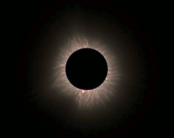 May include: A total solar eclipse, with the sun's corona visible as a bright halo around the black silhouette of the moon.