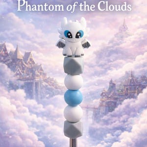 Pode incluir: Clipe de chupeta com um dragão branco com olhos e asas azuis, sobre uma série de contas cinzentas, brancas e azuis. O texto "White-Winged Phantom of the Clouds" está no topo. Acessório para bebé.