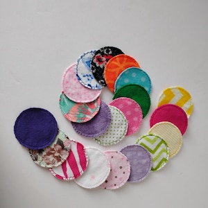 May include: A collection of 16 colorful reusable cotton rounds with various patterns, including polka dots, stripes, and floral designs. The rounds are arranged in a spiral pattern on a white background.