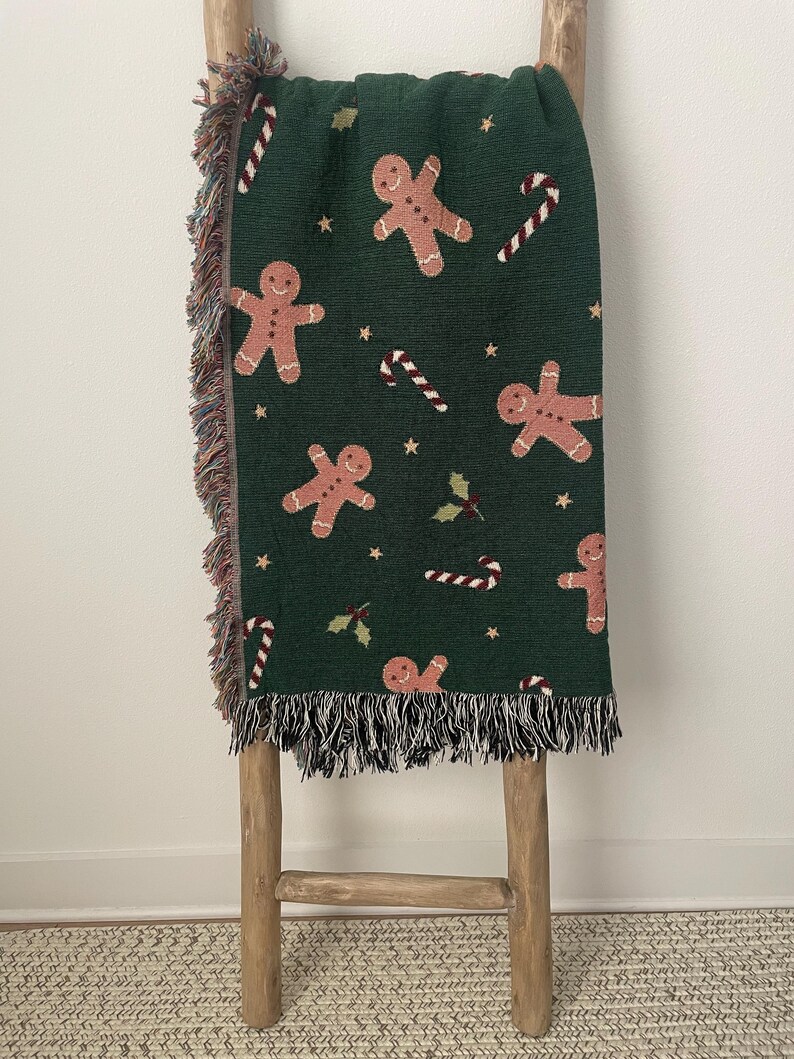 Cozy green woven Christmas throw blanket featuring gingerbread men, candy canes, holly leaves, and gold stars — festive holiday home décor gift.