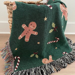 Festive green woven Christmas throw blanket with gingerbread men, candy canes, holly leaves, and star accents — cozy holiday décor or Christmas gift.