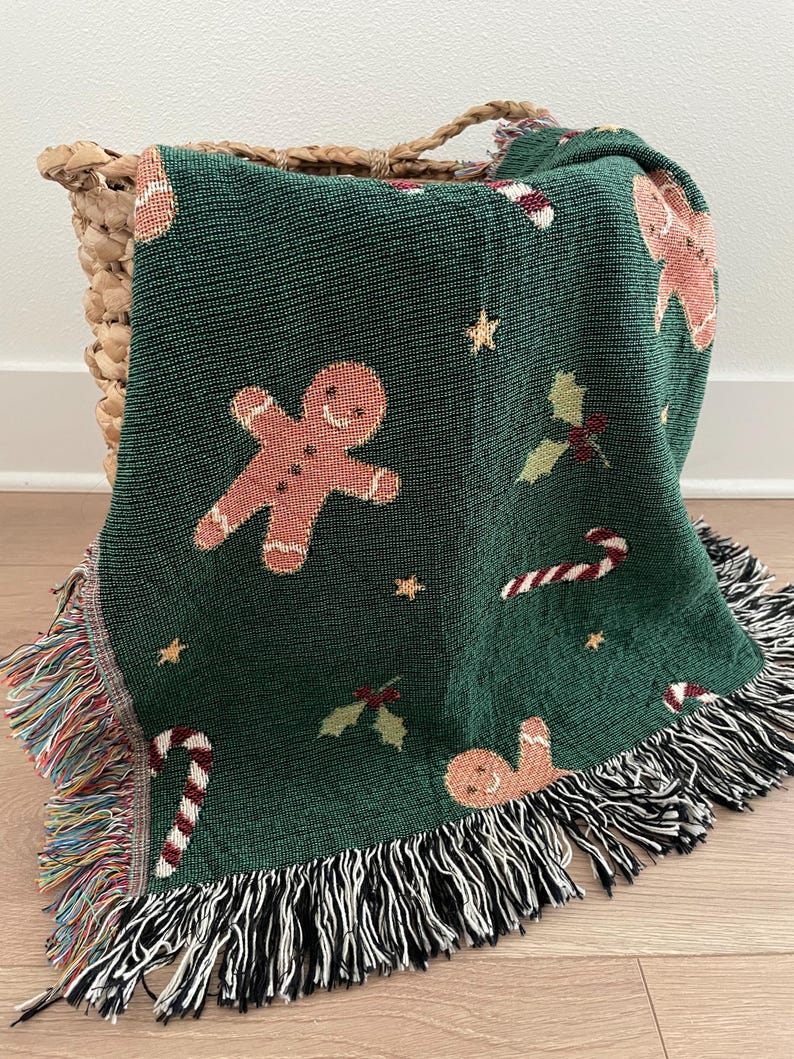 Festive green woven Christmas throw blanket with gingerbread men, candy canes, holly leaves, and star accents — cozy holiday décor or Christmas gift.