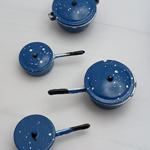 May include: Set of four blue enamel cookware with white speckles. The cookware includes a large pot with a lid and three smaller pots with lids.