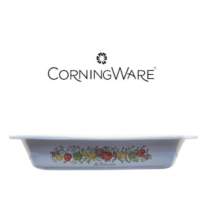 May include: A rectangular CorningWare baking dish with a light blue exterior and a central band featuring a colorful botanical illustration of vegetables and herbs, including the text Le Romarin printed in black script below the produce.
