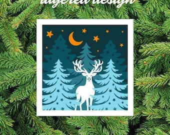 Puede incluir: Imagen cuadrada con un diseño en capas. Presenta un ciervo blanco con grandes astas, sobre un fondo de abetos azules, una luna creciente y estrellas. El texto "layered design" está en la parte superior.