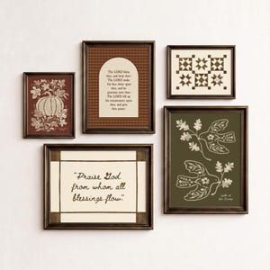 May include: A gallery wall set of five framed prints featuring a pumpkin illustration, a religious text in an arch, a geometric quilt pattern, a quote about blessings, and two birds with oak branches in dark brown, cream, and olive green tones.