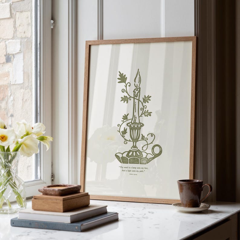 May include: A framed print with a green candle illustration in a decorative holder with floral details. The print has a light background with vertical stripes and a wooden frame. The quote "The word is a lamp unto my feet, And a light unto my path." is at the bottom.