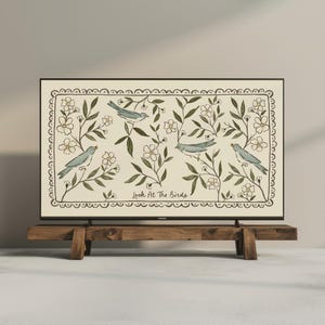 May include: A rectangular artwork featuring four blue birds perched among white flowers and green leaves, set against a cream background. The phrase "Look At The Birds" is printed at the bottom. The artwork is displayed on a wooden stand.