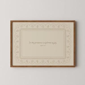 May include: A framed print with a light brown wooden frame. The print features a beige background with a decorative border and the text "In thy presence is fulness of joy" and "-Psalm 16:11" in a handwritten style font.
