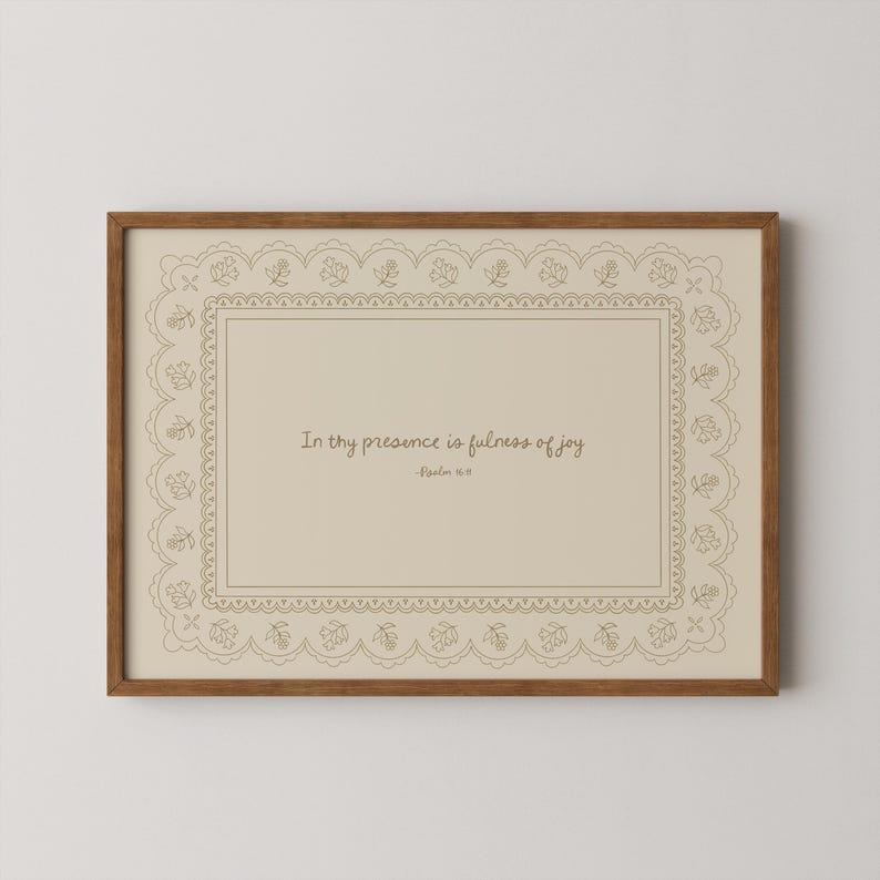 May include: A framed print with a light brown wooden frame. The print features a beige background with a decorative border and the text "In thy presence is fulness of joy" and "-Psalm 16:11" in a handwritten style font.