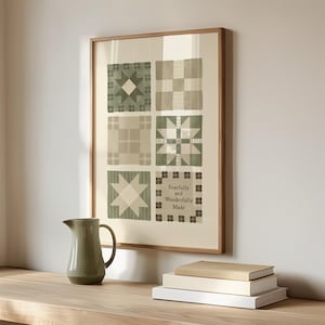 Pode incluir: Uma impressão emoldurada com seis desenhos de blocos de colcha em tons de verde e bege. A impressão inclui o texto "Fearfully and Wonderfully Made". Um jarro verde e uma pilha de livros estão em uma superfície de madeira.