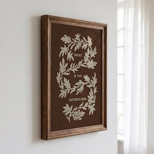 Könnte beinhalten: Ein rechteckiges Wandbild in einem dunkelbraunen Holzrahmen. Der Druck zeigt einen dunkelbraunen Hintergrund mit einer cremefarbenen botanischen Rankenillustration in S-Form, die den Text GREAT IS THY FAITHFULNESS in Creme enthält.