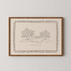 Puede incluir: Una impresión artística enmarcada con una ilustración de paisaje en blanco y negro de dos árboles en una colina. La obra de arte tiene un fondo crema, un borde decorativo y el texto "Be still, and know that I am God."