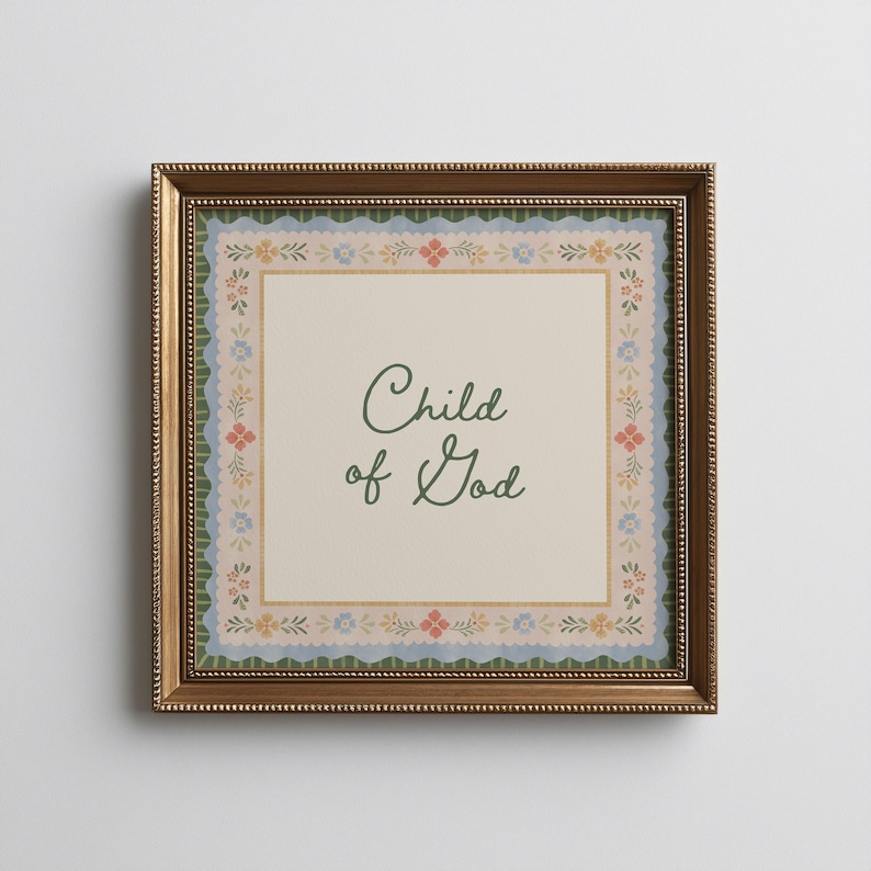 May include: A framed print featuring the text "Child of God" in a cursive font. The print has a cream background with a floral border in blue, pink, and yellow. The frame is a gold colour.