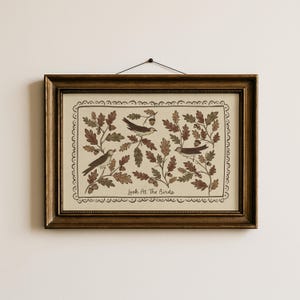May include: A rectangular wall art piece in a dark bronze frame featuring an illustration of three birds perched among oak leaves and acorns. The cream-colored print includes a decorative scalloped border and the text Look At The Birds.