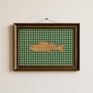 Könnte beinhalten: Gerahmter Kunstdruck mit einer stilisierten Fischillustration. Der Fisch ist orangefarben mit aufwendigen Details, vor einem grün-weiß karierten Hintergrund. Der Rahmen ist dunkelbraun.