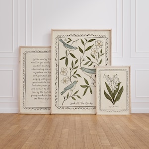 K&ouml;nnte beinhalten: Drei gerahmte Kunstdrucke mit botanischen und schriftlichen Themen. Ein Druck zeigt Text, ein anderer V&ouml;gel und Bl&auml;tter, und der dritte zeigt Maigl&ouml;ckchen. Die Rahmen sind helles Holz.