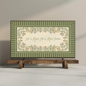 May include: A television screen shows a floral design with the words "He is Risen, He is Risen Indeed." The design is framed by a green border with vertical stripes. The TV is on a rustic wooden stand.