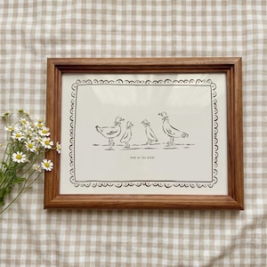 May include: A framed print with a line drawing of five birds, with the words "look at the birds" beneath. The artwork is in black and white, set against a cream background, and framed in a brown wooden frame.