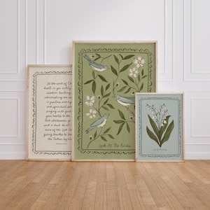 May include: Three framed art prints with botanical and bird illustrations. The largest print features birds and the text "Look At The Birds". The other prints display floral designs and script. The frames are light-coloured wood.