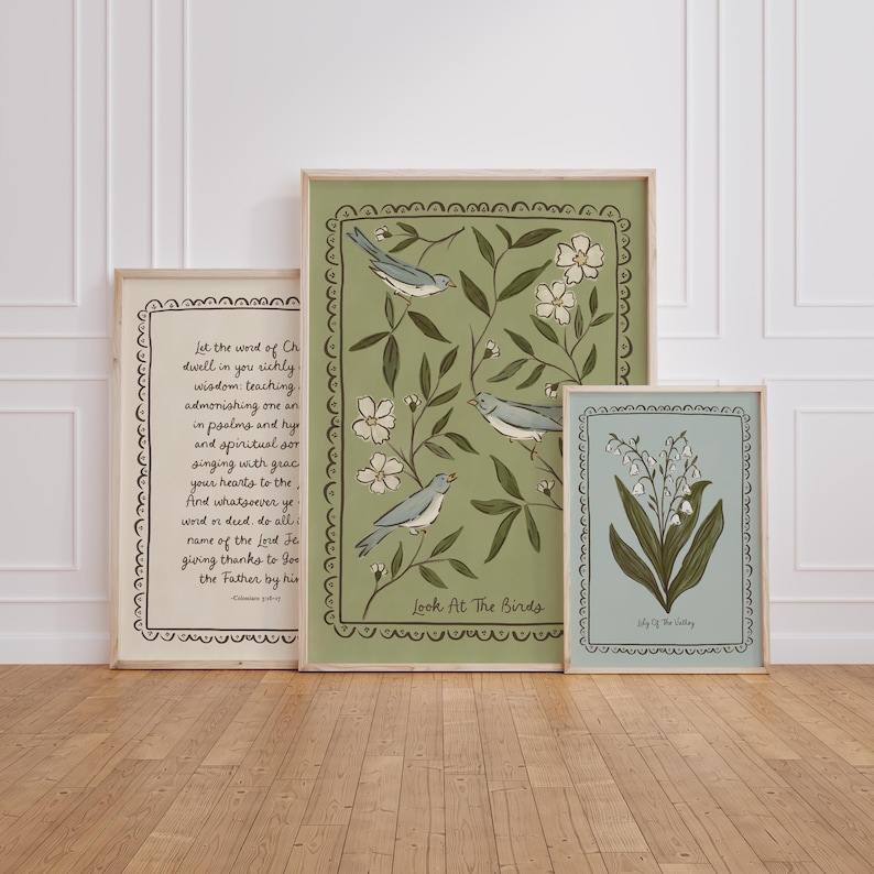 May include: Three framed art prints with botanical and bird illustrations. The largest print features birds and the text "Look At The Birds". The other prints display floral designs and script. The frames are light-coloured wood.