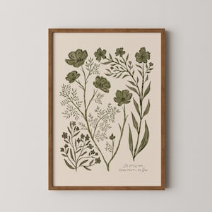 Puede incluir: Una impresión artística enmarcada con ilustraciones botánicas en tonos verdes sobre un fondo crema. La obra de arte incluye varios elementos florales y de follaje, con las palabras "Be still and know that I am God" en la parte inferior. El marco es de color marrón cálido.