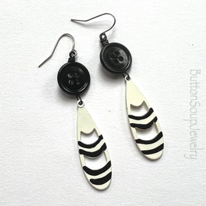 May include: Black and white striped teardrop shaped earrings with black buttons at the top.
