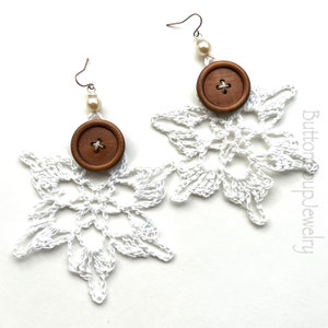 Peut inclure: Boucles d'oreilles en forme de flocon de neige en crochet blanc avec des boutons en bois brun et des accents de perles blanches. Button Up Jewelry.