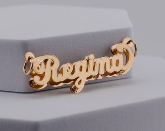 May include: Gold-tone pendant necklace with the name "Regina" spelled out in a cursive font.