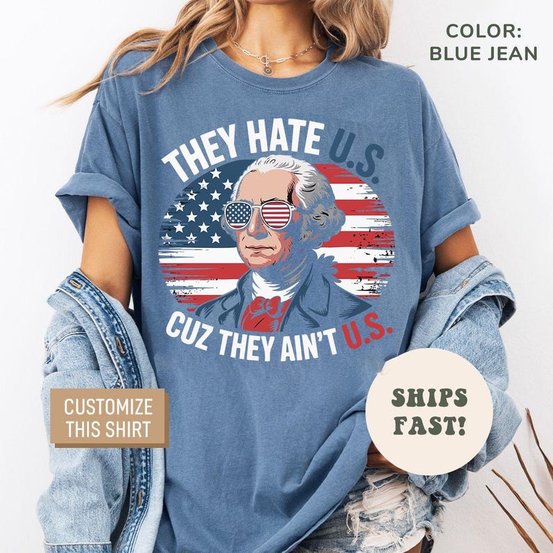 May include: Blue jean colored t-shirt with a graphic of George Washington wearing American flag sunglasses. The text reads "THEY HATE U.S. CUZ THEY AIN'T U.S." and "CUSTOMIZE THIS SHIRT".