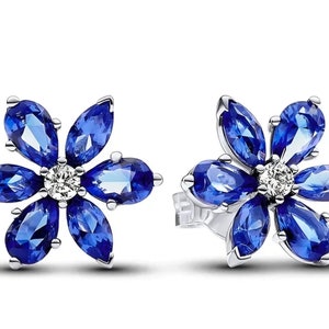 May include: A pair of silver flower-shaped earrings with blue gemstones and a small diamond in the center of each flower.