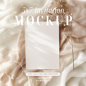 Maquette de carte blanche sur fond minimaliste et élégant en tissu de soie avec des ombres douces et des accents floraux délicats pour la papeterie de mariage de bébé