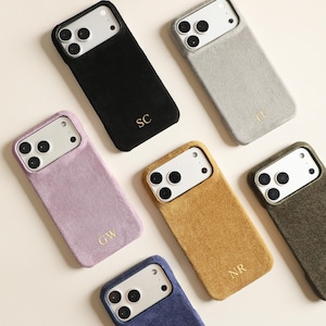 May include: Six rectangular smartphone cases with a textured, fabric-like finish in black, light gray, lavender, mustard yellow, olive green, and navy blue. Each case features a triple-lens camera cutout and gold-embossed initials: SC, TU, GW, and NR.