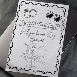 Op de afbeelding: Zwart-wit lijntekening uitnodiging met de naam "BRAYDEN" en de tekst "Will you be our Ring Bearer?" De uitnodiging bevat illustraties van een diamanten ring, zonnebril en een cartoon ringdrager.