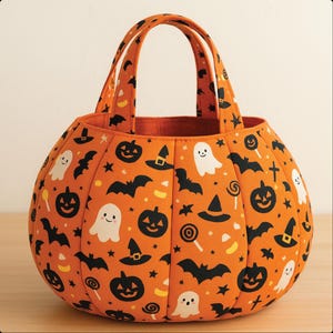 May include: Orange Halloween-themed tote bag with black bats, jack-o'-lanterns, witch hats, ghosts, and candy corn patterns. The bag has two handles and a pumpkin shape, perfect for trick-or-treating or seasonal decor.