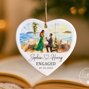 Puede incluir: Un adorno de cer&aacute;mica blanca en forma de coraz&oacute;n con una ilustraci&oacute;n en acuarela de una propuesta de matrimonio en la cubierta de un barco. El texto dice Sophia, un icono de coraz&oacute;n, Henry, ENGAGED y 09.26.2026. Cuelga de un cord&oacute;n dorado.