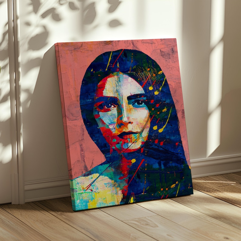 May include: Abstract portrait art print on canvas. The artwork features a woman's face with vibrant colors, including blue, red, yellow, and green, against a pink background. The painting has a modern, expressive style, with visible brushstrokes and paint splatters.